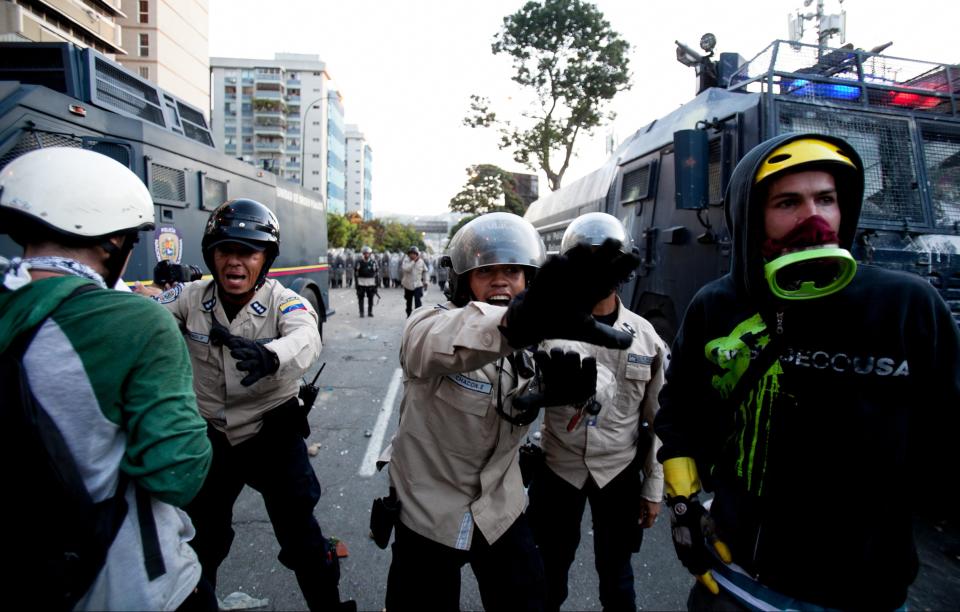 National Bolivarian Police officers yell at demonstrators to leave in Caracas, Venezuela, Saturday, Feb. 15, 2014. Venezuelan security forces backed by water tanks, tear gas and rubber bullets dispersed groups of anti-government demonstrators who tried to block Caracas' main highway Saturday evening. (AP Photo/Alejandro Cegarra)