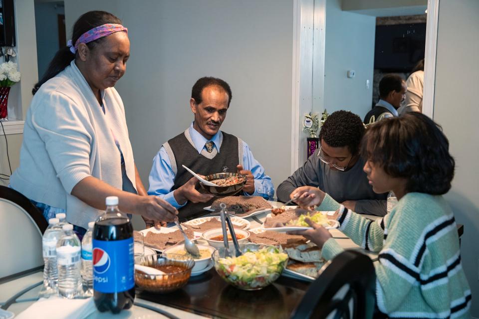 Abeba Kahsay (from left), her husband Mengsteab Aregay Gebremariam, their son Mikias, 14, and daughter Sina, 11, have homemade injera flatbread with various toppings for lunch after Sunday service at Lakeview Church on Jan. 16, 2022, in Indianapolis. More than a decade after Gebremariam and Kahsay immigrated here as refugees from Eritrea, Gebremariam is learning to speak English through a "Pathway to Literacy" pilot program coordinated by the Immigrant Welcome Center and other area organizations.