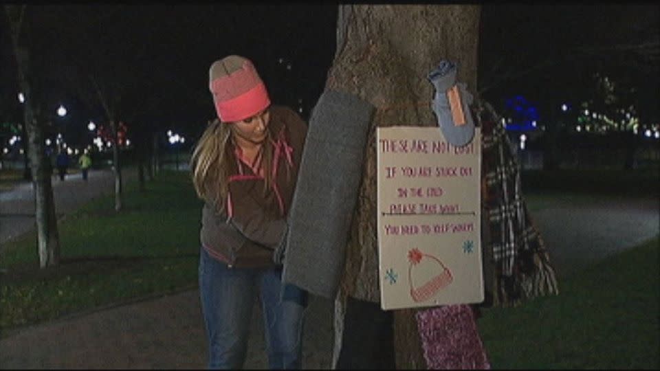 A woman fixes gloves and hats to a tree for homeless people to pick up if they are cold. Photo: AP