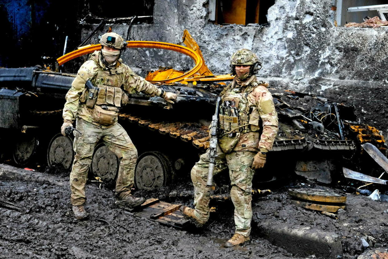 Des soldats ukrainiens devant une carcasse de char détruit par l'artillerie russe.  - Credit:MAXPPP / MAXPPP/MAXPPP