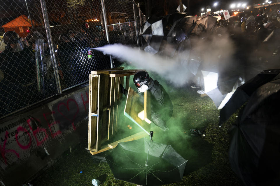 A demonstrator is shot with less-than-lethal marking rounds and tear gas during a standoff with police during a protest decrying the shooting death of Daunte Wright, outside the Brooklyn Center Police Department, Wednesday, April 14, 2021, in Brooklyn Center, Minn. (AP Photo/John Minchillo)