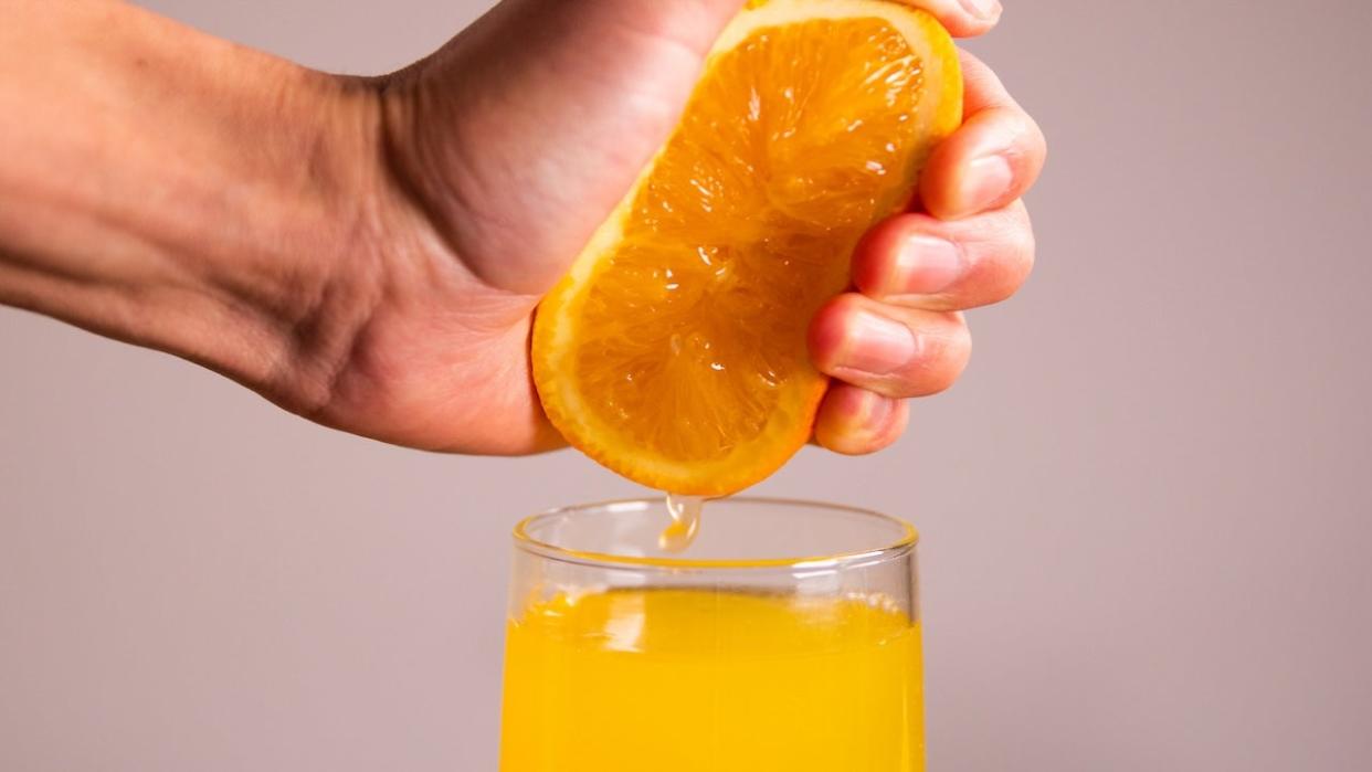 Hand squeezing fresh orange juice