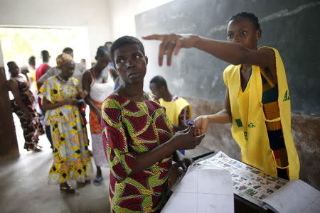 An electoral officer points at a polling booth to a voter during a presidential election at a polling station in Cotonou, Benin, March 6, 2016. REUTERS/Akintunde Akinleye