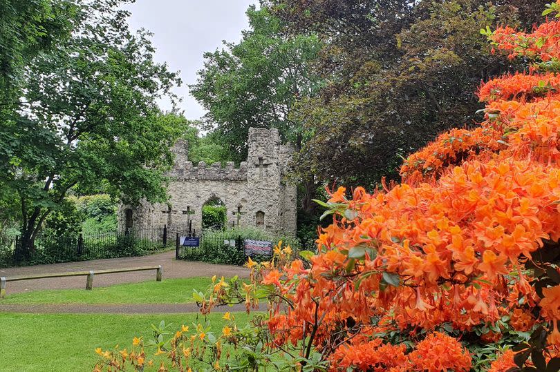 Flowers and the stone gatehouse at Reigate Castle Grounds