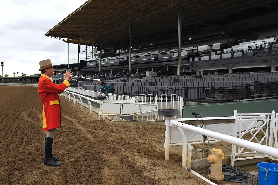 Bugler Jay Cohen plays "First Call" as he calls the riders to post for the first race at Santa Anita Park to empty stands Saturday, March 14, 2020, in Arcadia, Calif. (AP Photo/Mark J. Terrill)