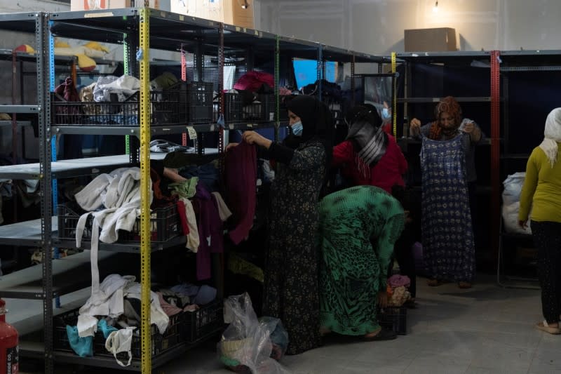 Women look at donated clothes inside the Ritsona camp for refugees and migrants