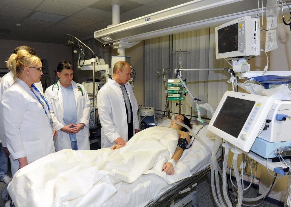 In this photo provided by RIA Novosti Kremlin, Russian President Vladimir Putin, center, speaks to skier Maria Komissarova in a hospital in Krasnaya Polyana, Russia, on Saturday, Feb. 15, 2014. The 23-year-old Russian ski cross racer fractured her spine during a training session Saturday and underwent a 6 1/2 hour surgery. (AP Photo/RIA Novosti, Mikhail Klimentyev, Presidential Press Service)