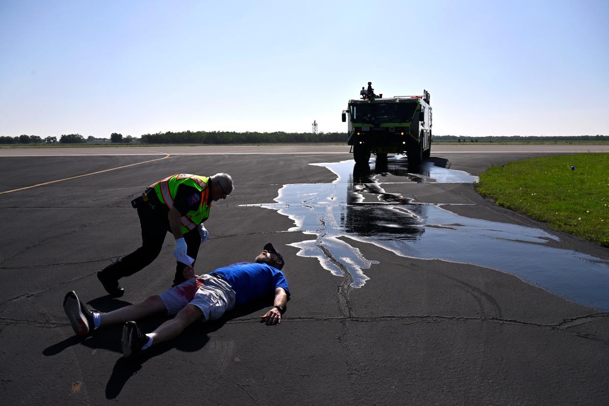 Jerry Thayer lays on the tarmac at Abilene Regional Airport as paramedic checks on him during an airport emergency exercise Wednesday.