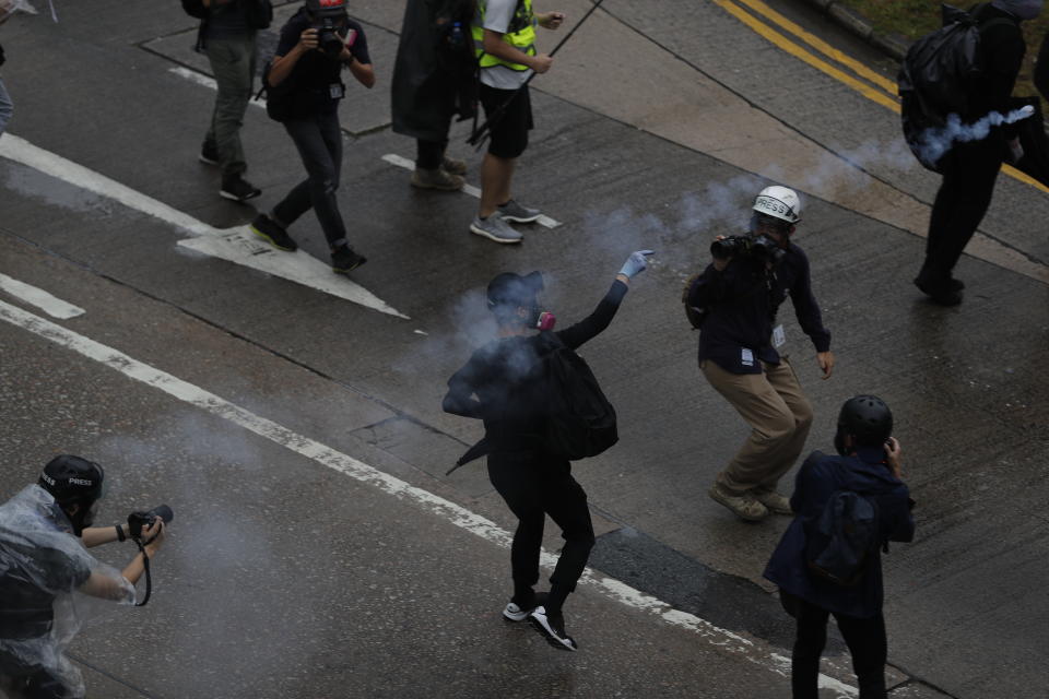 A protestor throws back teargas shell at police in Hong Kong, Sunday, Oct. 6, 2019. Shouting "Wearing mask is not a crime," tens of thousands of protesters braved the rain Sunday to march in central Hong Kong as a court rejected a second legal attempt to block a mask ban aimed at quashing violence during four months of pro-democracy rallies. (AP Photo/Vincent Thian)