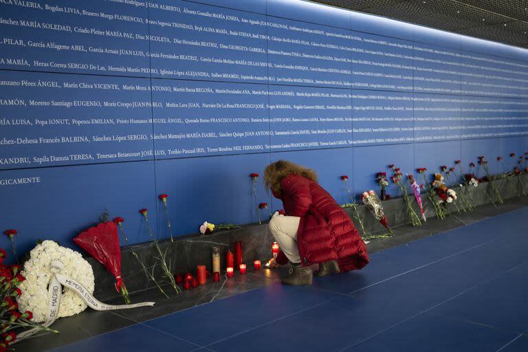 Una mujer enciende una vela en un memorial para las víctimas del atentado en la estación de tren de Atocha en Madrid, España, el lunes 11 de marzo de 2024. 