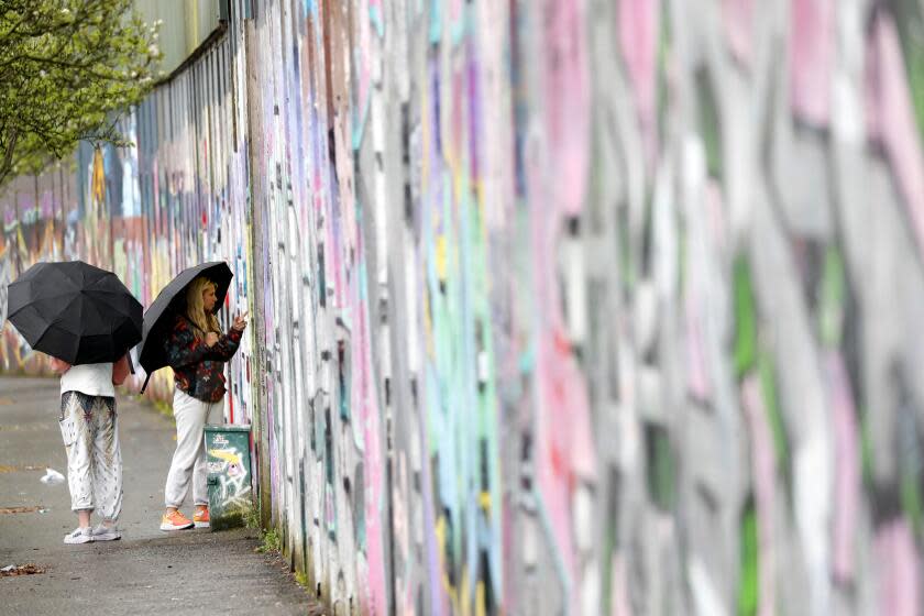 Tourists sign the "peace walls" that still separate some nationalist and unionist neighborhoods in west Belfast, Northern Ireland, Wednesday, April 5, 2023. It has been 25 years since the Good Friday Agreement largely ended a conflict in Northern Ireland that left 3,600 people dead. (AP Photo/Peter Morrison)