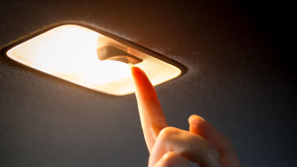 Closeup photo of woman turning light on in car salon.