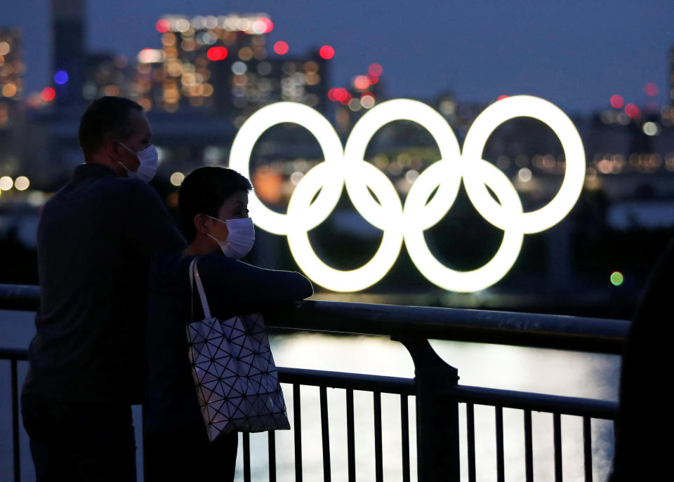 The giant Olympic rings are seen in front of the visitors wearing protective face masks, only a quarter of the Japanese public are excited about next year's reorganised Games according to one survey