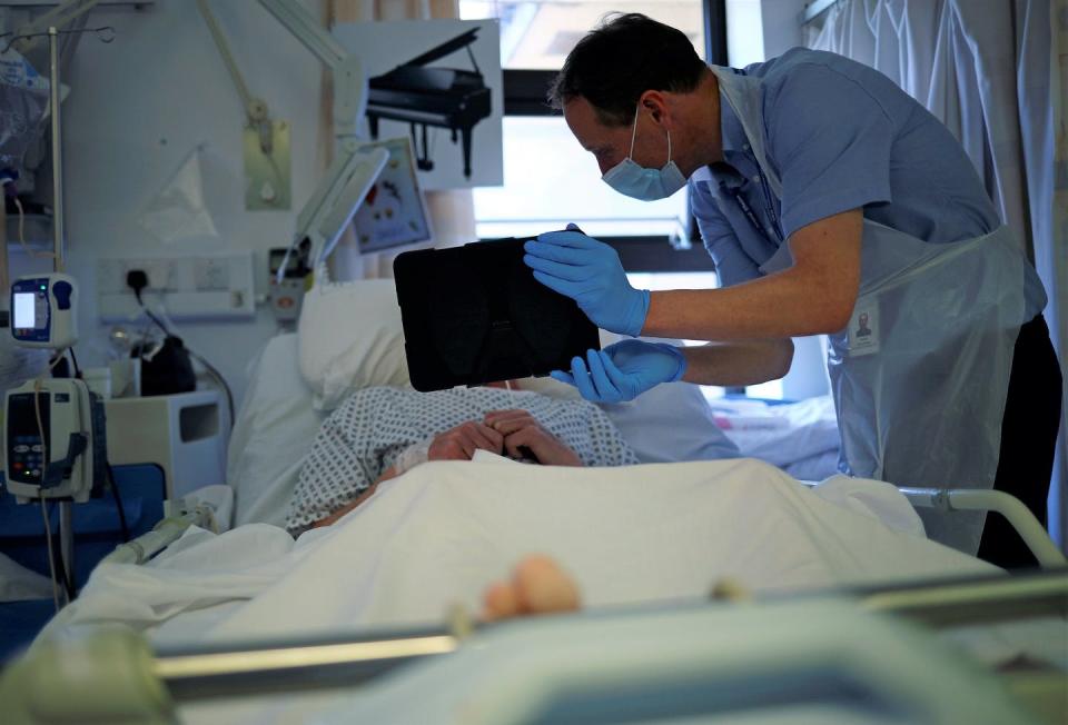 <span class="caption">A chaplain uses an iPad to help a patient communicate with family members who are unable to visit due to hospital visiting restrictions amid the coronavirus pandemic.</span> <span class="attribution"><a class="link " href="http://apimages.com" rel="nofollow noopener" target="_blank" data-ylk="slk:Hannah McKay/Pool Photo via AP;elm:context_link;itc:0;sec:content-canvas">Hannah McKay/Pool Photo via AP</a></span>