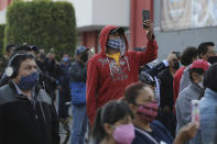 People take photos of subway cars dangling at an angle from a collapsed elevated section of the metro, in Mexico City, Tuesday, May 4, 2021. The elevated section collapsed late Monday killing at least 23 people and injuring at least 79, city officials said. (AP Photo/Fernando Llano)