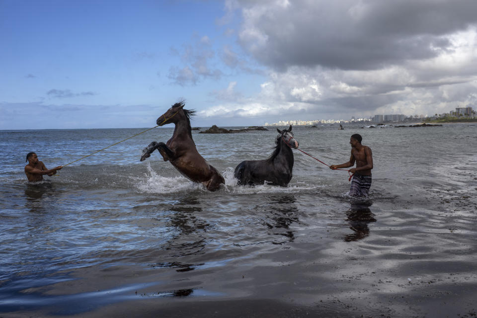 Albert Franca, right, and Ruan Gabriel wash their pet horses in the Atlantic Ocean in Salvador, Bahia state, Brazil, Thursday, Sept. 15, 2022. The young men said they live near the ocean where they ride their horses once a month for a swim. (AP Photo/Rodrigo Abd)