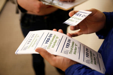 An employee of the advocacy group Basic Rights Oregon hands out stickers during an Oregon Driver and Motor Vehicle department public hearing on the rights of transgender people as the state considers adding a third gender choice to driver's licenses and identification cards, in Portland, Oregon, May 10, 2017. REUTERS/Terray Sylvester