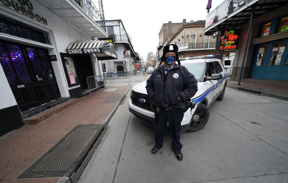 A police officer stands guard on a nearly deserted Bourbon Street during Mardi Gras in the French Quarter of New Orleans, Tuesday, Feb. 16, 2021. Coronavirus-related limits on access to Bourbon Street, shuttered bars and frigid weather all prevented what New Orleans usually craves at the end of Mardi Gras season — streets and businesses jam-packed with revelers. (AP Photo/Gerald Herbert)