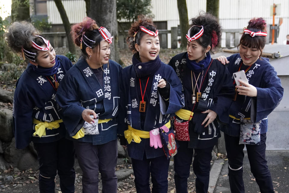 In this Tuesday, Dec. 3, 2019, photo, participants clad in traditional happi coats prepare for a selfie before the Chichibu Night Festival in Chichibu, Japan. This two-day festival has its roots in an older tradition of villagers giving thanks to the nearby mountain god for helping them during the planting and harvesting season, according to Minoru Sonoda, the chief priest of the shrine. (AP Photo/Toru Hanai)