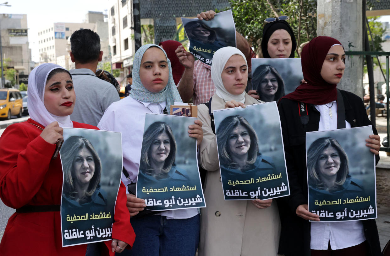 Palestinians hold posters with Abu Akleh’s image.
