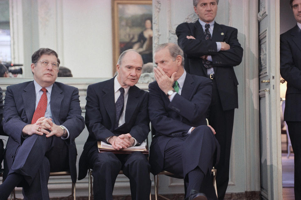 FILE - In this Nov. 21, 1990 file photo, Secretary of State James Baker whispers to National Security Advisor Brent Scowcroft during an impromptu press conference by President George H. W. Bush in Paris. At left is White House Chief of Staff John Sununu. A longtime adviser to Presidents Gerald Ford and George H.W. Bush has died. Brent Scowcroft was 95. A spokesperson for the late President Bush says Scowcroft died Thursday of natural causes at his home in Falls Church, Virginia.(AP Photo/Scott Applewhite)