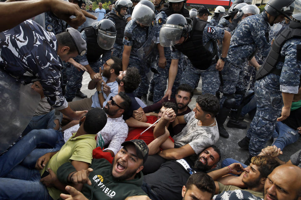 Police negotiate with anti-government protesters to unblock a main highway in Beirut, Lebanon, Saturday, Oct. 26, 2019. The removal of the roadblocks on Saturday comes on the tenth day of protests in which protesters have called for civil disobedience until the government steps down. (AP Photo/Bilal Hussein)