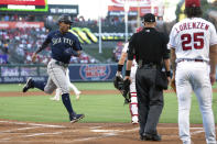 Seattle Mariners Julio Rodriguez, left, scores on a single by Eugenio Suarez as Los Angeles Angels starting pitcher Michael Lorenzen, right, watches along with home plate umpire Will Little during the first inning of a baseball game Friday, June 24, 2022, in Anaheim, Calif. (AP Photo/Mark J. Terrill)