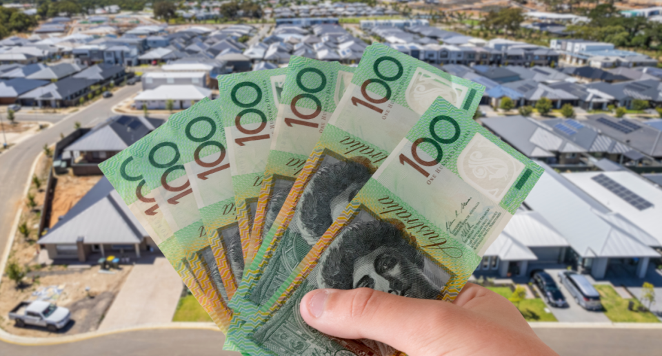 Australian $100 notes in front of homes