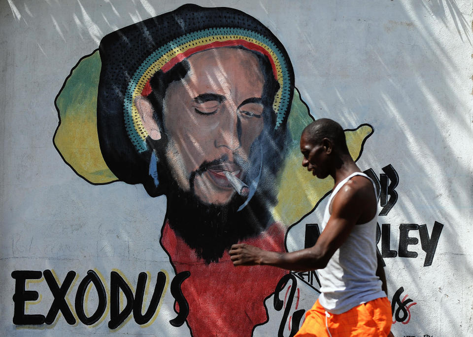 A man walks past a mural of late musician Bob Marley in Kingston on February 8, 2009. Marley, who was born in 1945 and died in 1981, remains the most widely known and revered performer of reggae music and is also credited for helping spread Jamaican music to a worldwide audience. Marley's best known hits include "I Shot the Sheriff", "No Woman, No Cry", "Exodus", "Could You Be Loved", "Stir It Up", "Jamming", "Redemption Song", "One Love" and together with The Wailers "Three Little Birds", as well as the posthumous releases "Buffalo Soldier" and "Iron Lion Zion." The compilation album, Legend, released in 1984, three years after his death, is the best-selling reggae album ever with sales of more than 20 million copies.       AFP PHOTO/Jewel SAMAD (Photo credit should read JEWEL SAMAD/AFP via Getty Images)