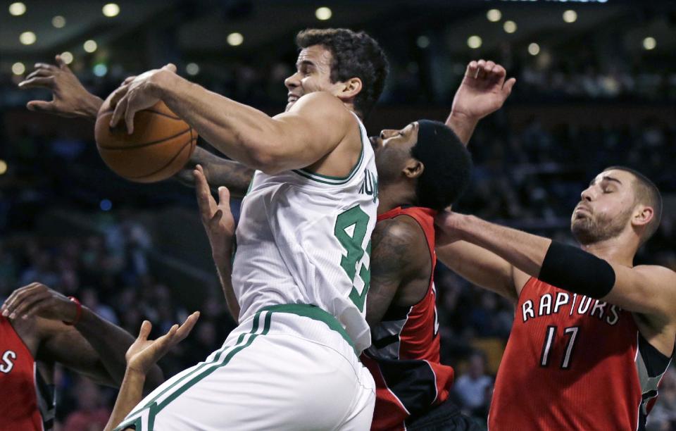 Boston Celtics forward Kris Humphries, front, grabs a rebound against Toronto Raptors center Jonas Valanciunas, right, and forward John Salmons, rear, during the first quarter of an NBA basketball game in Boston, Wednesday, Jan. 15, 2014. (AP Photo/Charles Krupa