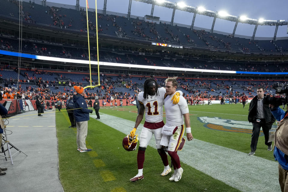 Washington Football Team wide receiver Cam Sims (11) walks off the field with quarterback Taylor Heinicke after an NFL football game against the Denver Broncos, Sunday, Oct. 31, 2021, in Denver. The Broncos won 17-10. (AP Photo/David Zalubowski)