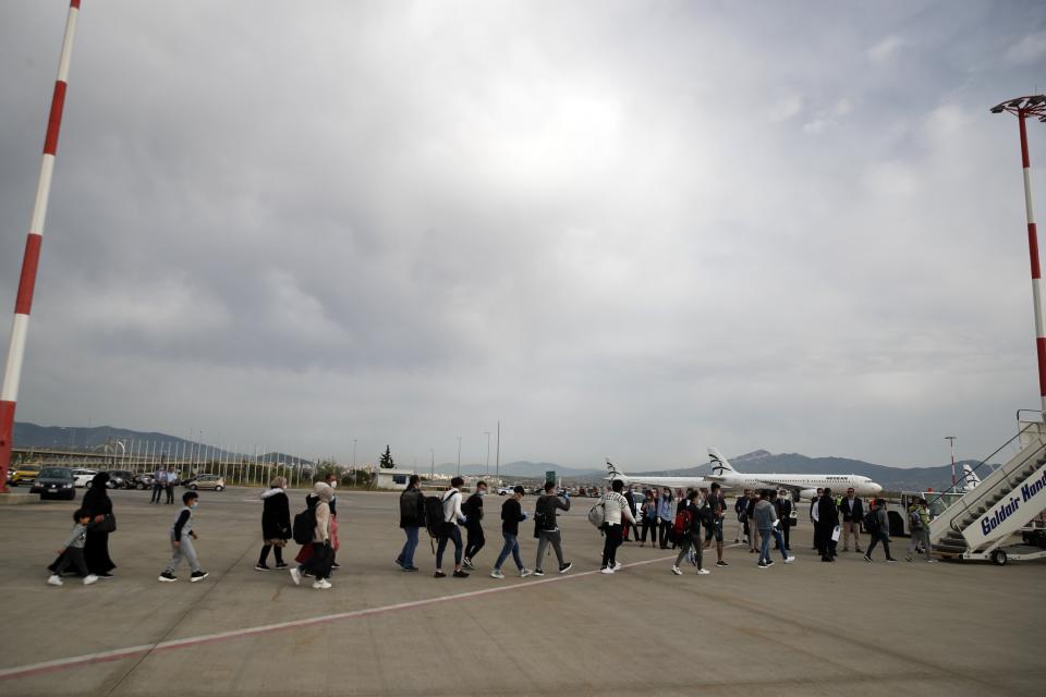 Migrants wearing face masks to prevent the spread of the coronavirus, board an airplane bound for Britain at the Eleftherios Venizelos International Airport in Athens, on Monday, May 11, 2020. Sixteen unaccompanied children refugees and 34 migrants were relocated as part of a migrant reunification plan agreed between the two countries. (AP Photo/Thanassis Stavrakis)