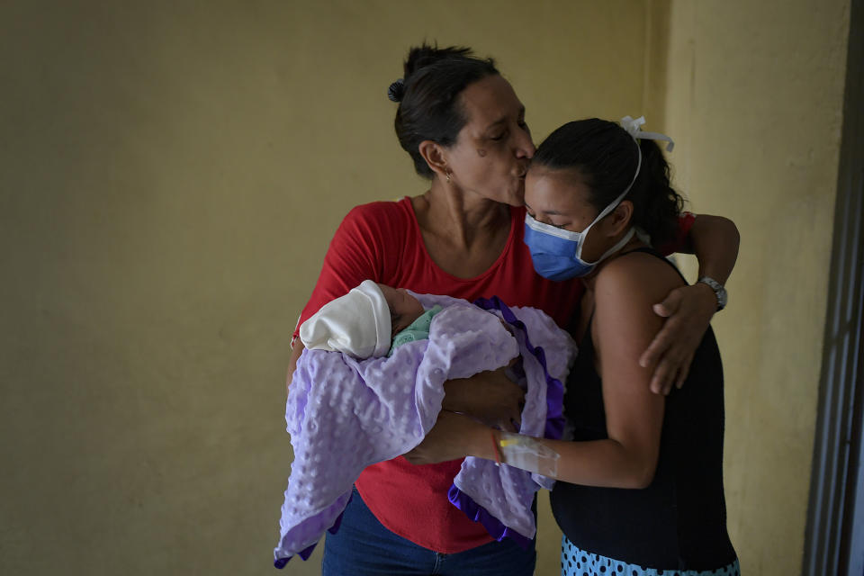 Nelida Lopez kisses her daughter, first-time mom Ada Mendoza, while cradling newborn granddaughter Peyton, after the two arrived home from the hospital, in the Catia neighborhood of Caracas, Venezuela, Saturday, Sept. 12, 2020. The 24-year-old mother carried her baby to term in the midst of Venezuela's worst economic crisis and the COVID-19 pandemic that has disrupted the lives of millions. (AP Photo/Matias Delacroix)