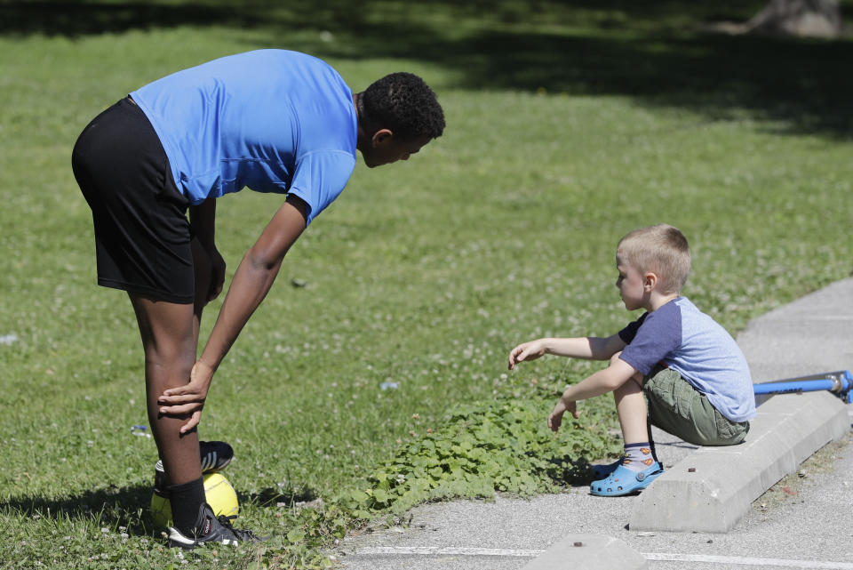Belachew Neal talks with his younger brother, Elisha, as they prepare to play soccer at Garfield Park, Sunday, June 14, 2020, in Indianapolis. The Associated Press discussed race with six white couples who have adopted or have custody of Black children. These parents are trying to help their children understand race in America while getting an accelerated course themselves. (AP Photo/Darron Cummings)