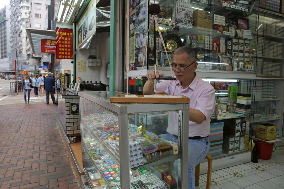 In this April 18, 2019, photo, Cheung Shun-king, 65-year-old maker of the popular table-top game mahjong tiles, engraves a character on a tile in his decades-old store in Kowloon's old neighborhood of Hong Kong. Hand-carved mahjong tiles is a dying art in Hong Kong. (AP Photo/Kin Cheung)