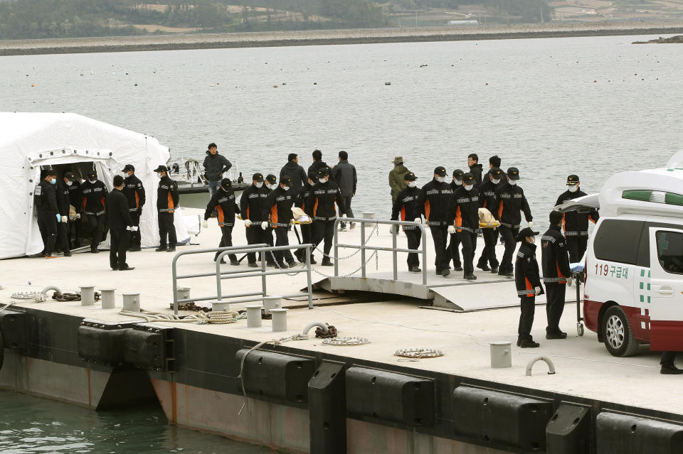 Emergency workers carry the bodies of passengers aboard the Sewol ferry which sank in the water off the southern coast, upon their arrival at a port in Jindo, South Korea, Tuesday, April 22, 2014. As divers continue to search the interior of the sunken ferry, the number of confirmed deaths has risen, with about 220 other people still missing. (AP Photo/Ahn Young-joon)