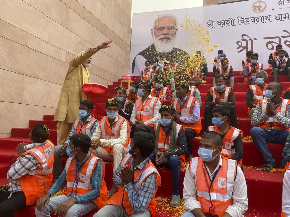 Indian Prime Minister Narendra Modi, showers flower petals on workers during the inauguration of Kashi Vishwanath Dham Corridor, a promenade that connects the sacred Ganges River with the centuries-old temple dedicated to Lord Shiva in Varanasi, India, Monday, Dec. 13, 2021. (AP Photo/Rajesh Kumar Singh)