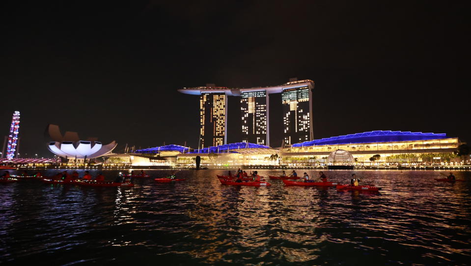 Participants of the Sunset Paddle event by People's Association rowing past Marina Bay Sands. (PHOTO: People's Association PAssion Wave)