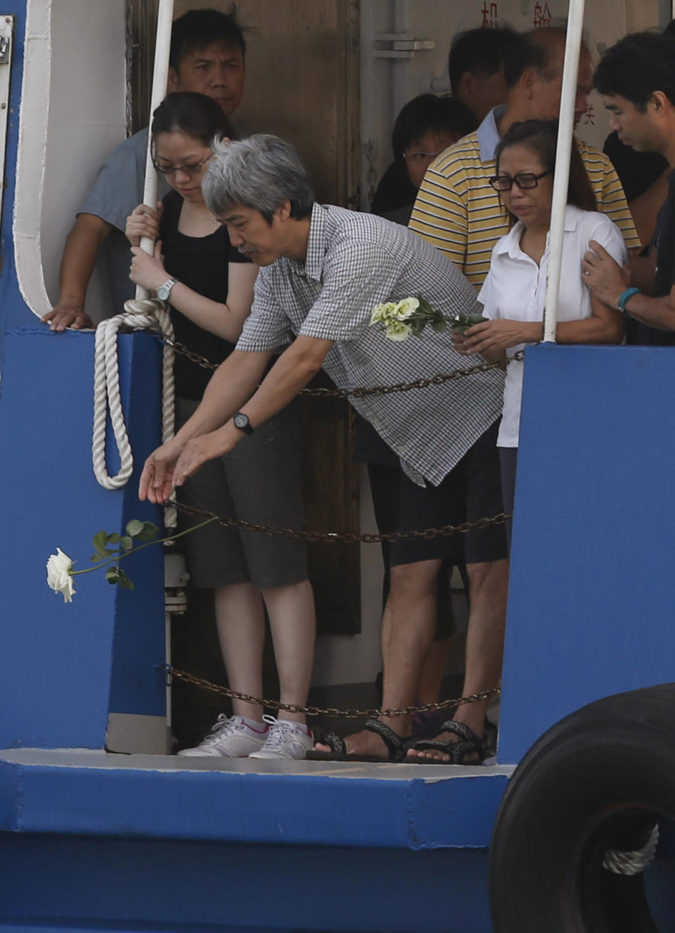 Relatives of boat collision victims throw flowers into the sea Thursday, Oct. 4, 2012 as they pay tribute to the ill-fated people aboard a boat that sank Monday night near Lamma Island, off the southwestern coast of Hong Kong Island. A show of concern by Beijing over the boat collision that killed dozens of people in Hong Kong this week has backfired, further damaging the communist government's image in the former British colony. (AP Photo/Kin Cheung)