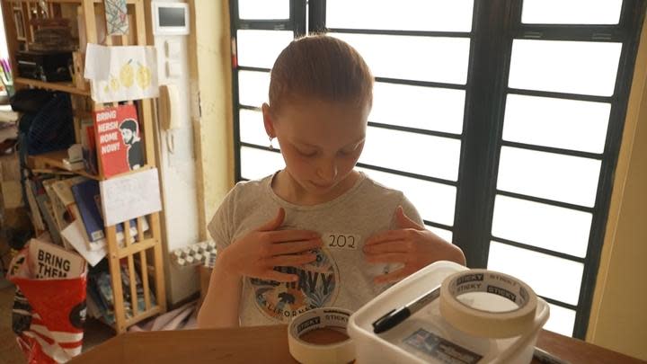 Dariel Bardach-Goldstein tapes the number 202 to her chest before heading to school in Jerusalem, representing how many days her cousin has been held hostage by Hamas.  / Credit: CBS News