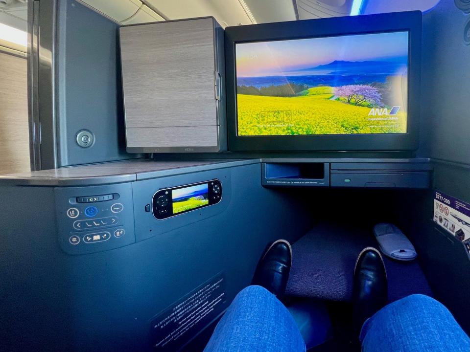 A view facing the TV and cubby in the cabin, with the writer's feet on the footrest.