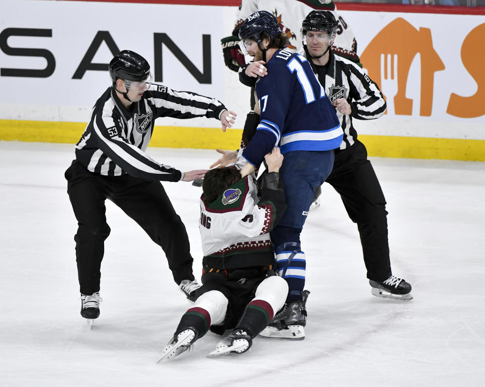 Officials break up a fight between Arizona Coyotes' Michael Kesselring (5) and Winnipeg Jets' Adam Lowry (17) during the first period of an NHL hockey game in Winnipeg, Manitoba on Sunday, Feb. 25, 2024. (Fred Greenslade/The Canadian Press via AP)