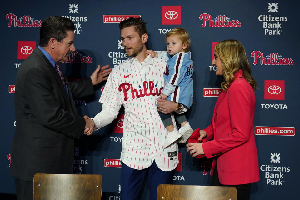 Newly acquired Philadelphia Phillies shortstop Trea Turner, center, greets manager Rob Thomson, left, after his introductory news conference, Thursday, Dec. 8, 2022, in Philadelphia. At right is Turner's wife, Kristen, and son, Beckham. (AP Photo/Matt Slocum)