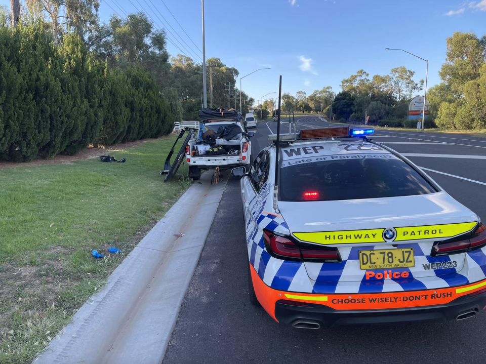 A NSW police car stopped on the side of a road with the ute with an obstructed number plate.
