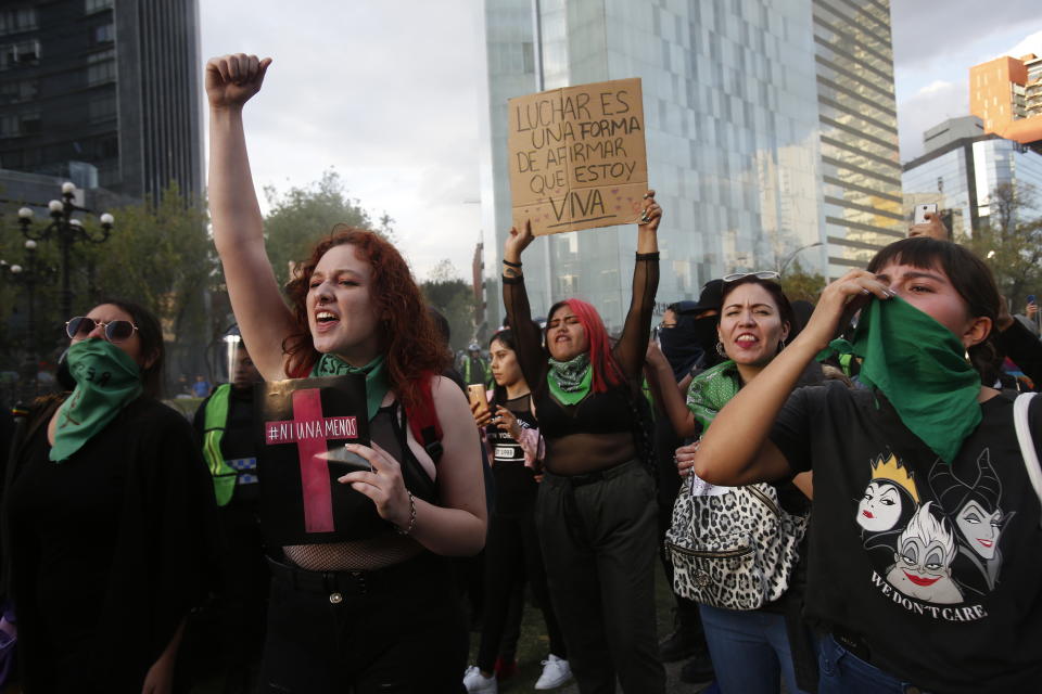 Women, one holding a sing that reads in Spanish "Fighting is way to reaffirm that I am alive," protest against the latest murder of two women, in Mexico City, Saturday, Jan. 25, 2020. During the past couple of weeks two women activists, attorney Yunuen Lopez Sanchez and Isabel Cabanillas de la Torre where murdered by unknown assailants. (AP Photo/Ginnette Riquelme)