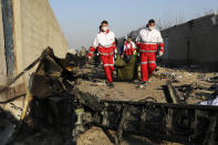 Rescue workers carry the body of a victim of an Ukrainian plane crash among debris of the plane in Shahedshahr, southwest of the capital Tehran, Iran, Wednesday, Jan. 8, 2020. A Ukrainian airplane carrying 176 people crashed on Wednesday shortly after takeoff from Tehran's main airport, killing all onboard. (AP Photo/Ebrahim Noroozi)