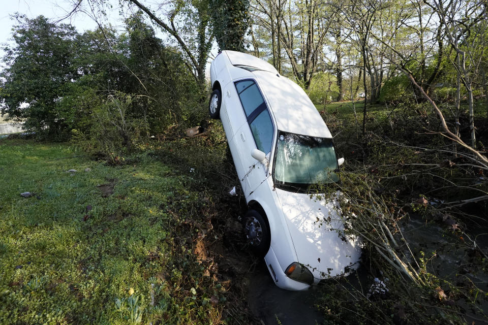 A car that was carried by floodwaters leans against a tree in a creek Sunday, March 28, 2021, in Nashville, Tenn. Heavy rain across Tennessee flooded homes and roads as a line of severe storms crossed the state. (AP Photo/Mark Humphrey)