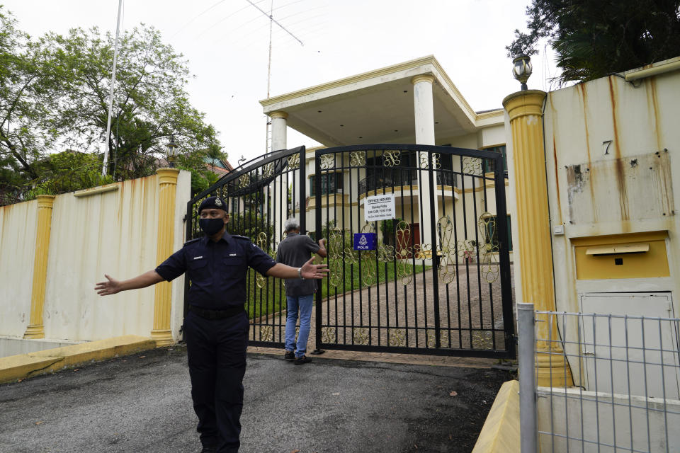 A staff locks the front gate of North Korean embassy in Kuala Lumpur, Sunday, March 21, 2021. Malaysia on Friday ordered all North Korean diplomats to leave the country within 48 hours, an escalation of a diplomatic spat over Malaysia's move to extradite a North Korean suspect to the United States on money laundering charges. (AP Photo/Vincent Thian)