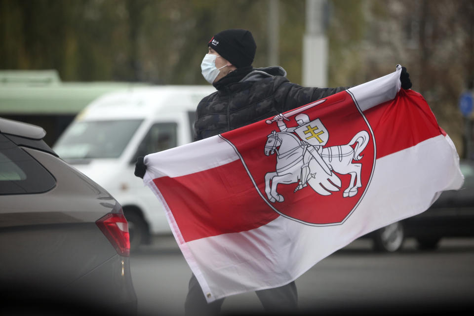 FILE In this file photo taken on Sunday, Nov. 22, 2020, A man wearing a face mask to help curb the spread of the coronavirus holds an old Belarusian national flag during an opposition rally to protest the official presidential election results in Minsk, Belarus. A wave of COVID-19 has spread through Belarusian jails packed with people imprisoned for taking part in four months of protests against the nation’s authoritarian president. Activists, who tested positive after being released, describe massively overcrowded cells and the lack of basic amenities, and some even allege that the authorities have deliberately spread contagion among political prisoners. (AP Photo, File)