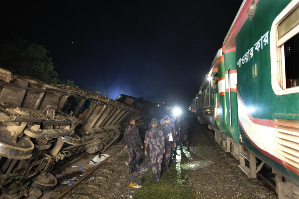 Policemen stand guard at the site of an accident where a cargo train has hit a passenger train at Bhairab, Kishoreganj district, Bangladesh, Monday, Oct. 23, 2023, leaving more than dozen people dead and scores injured. (AP Photo/Mahmud Hossain Opu)